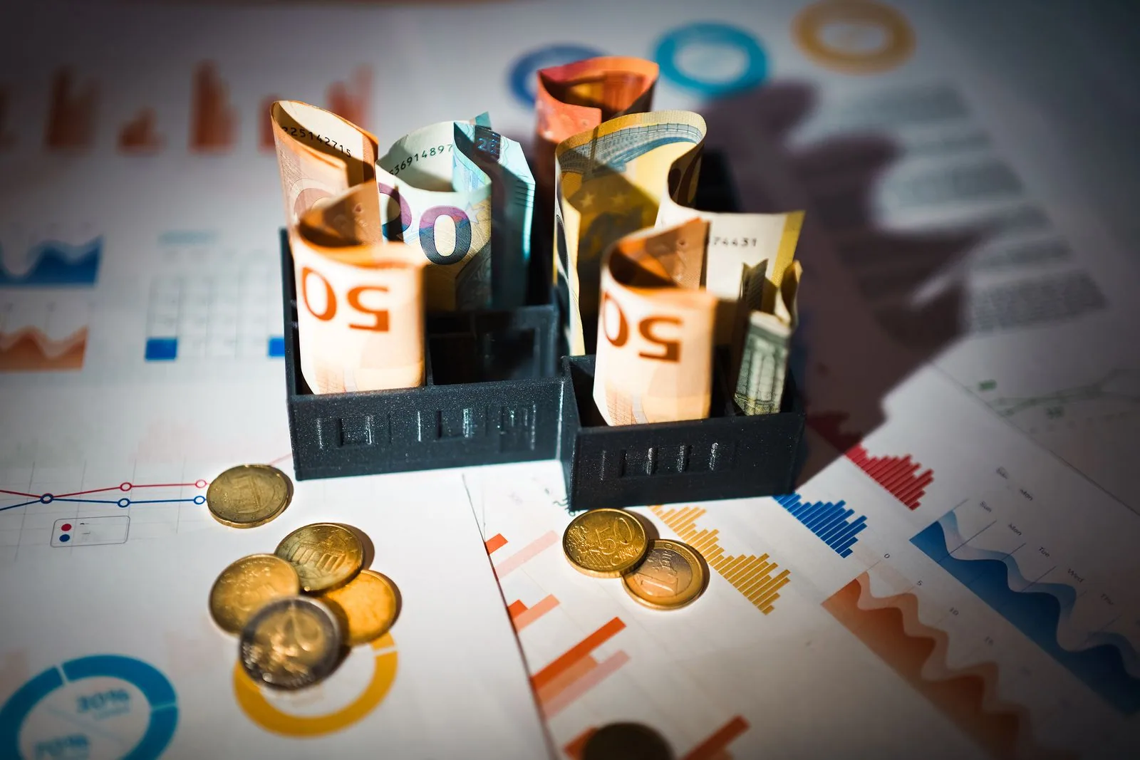 Euro-Banknoten und Münzen auf Finanzcharts