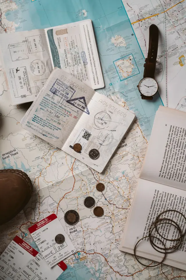 Passaporte, mapa e acessórios de viagem organizados sobre uma superfície.