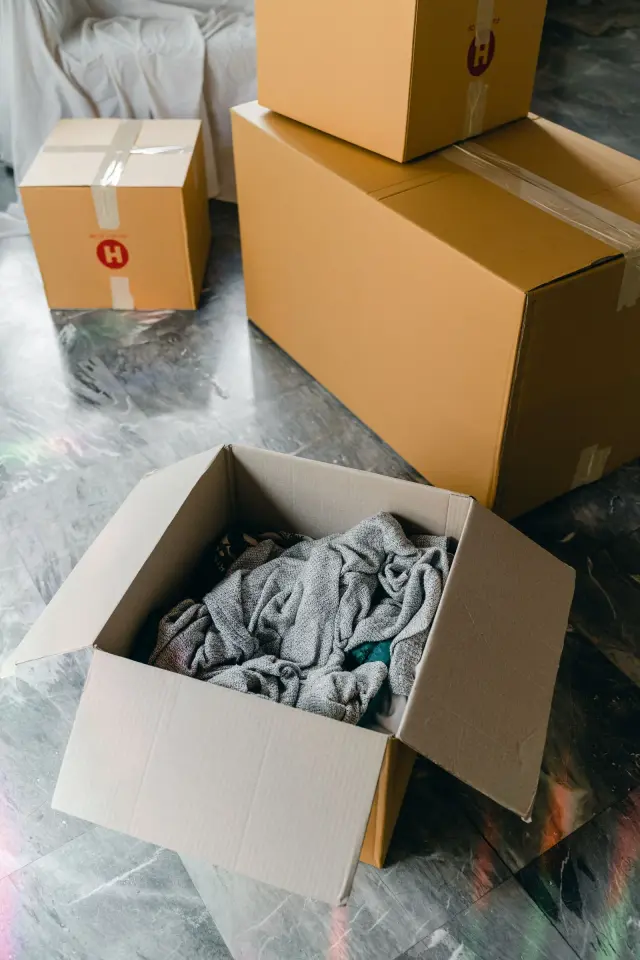 Caixas de cartão abertas e fechadas no chão de uma casa durante uma mudança.