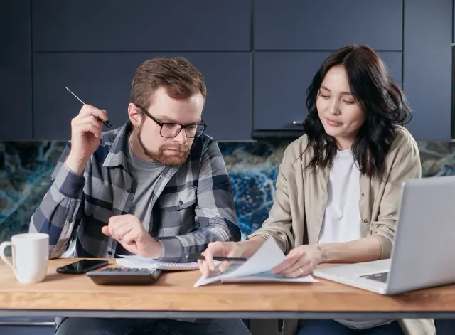 Casal a analisar despesas com documentos e calculadora.